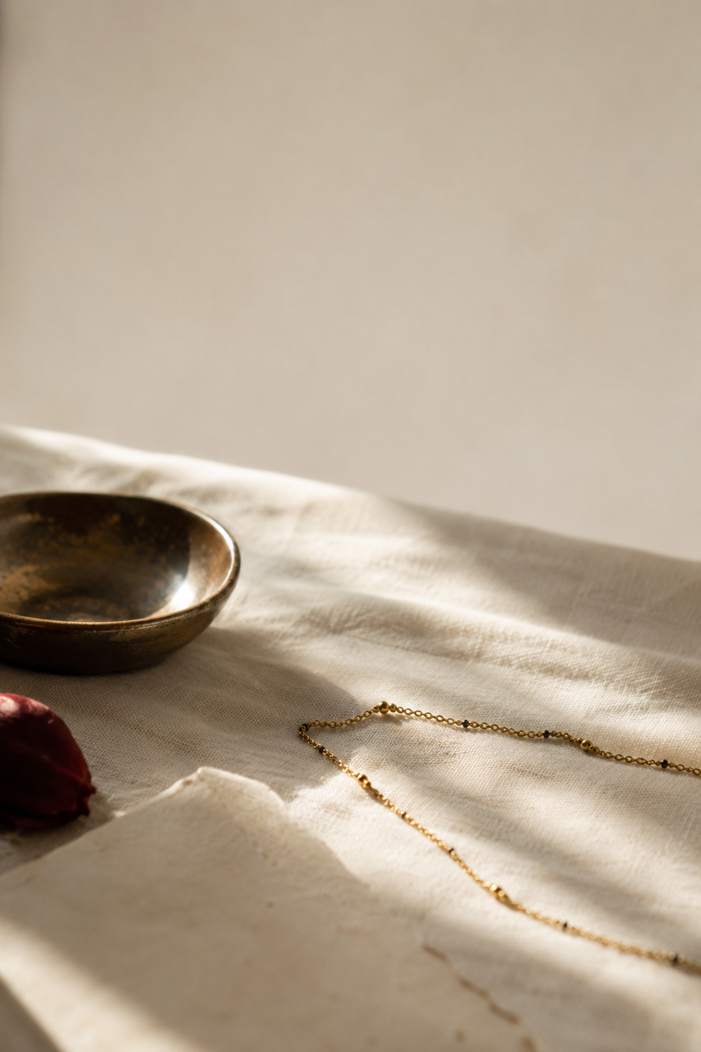 A delicate 18k gold mangalsutra chain laid across cream linen fabric, lit by soft morning light